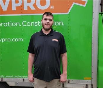 photo of Jeremy standing in front of a green SERVPRO box truck