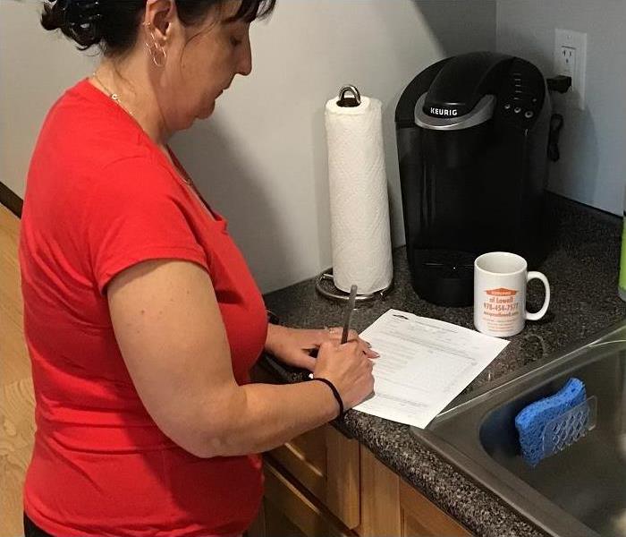 Lady signing paperwork in her kitchen